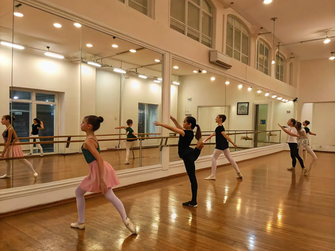 A brightly lit dance studio where students are practicing a choreographed routine, with the instructor providing guidance and feedback.